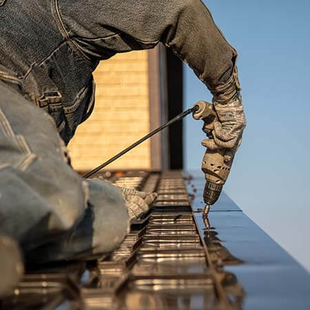 A man doing work with a drill on a roof A man doing work with a drill on a roof